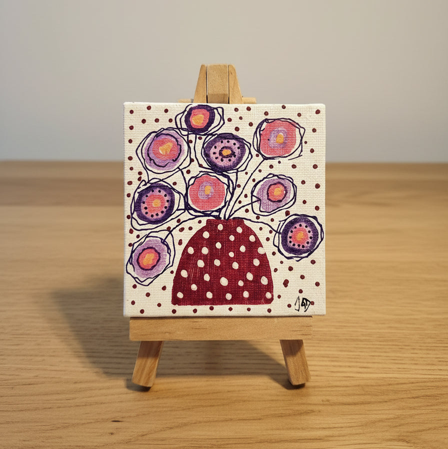 Small painting of flowers in a polka dot vase on a wooden easel